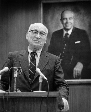 News_Gazette_4 Arnold Beckman stands at a podium, speaking into three microphones, when announcing his $40 million gift to found the Beckman Institute.